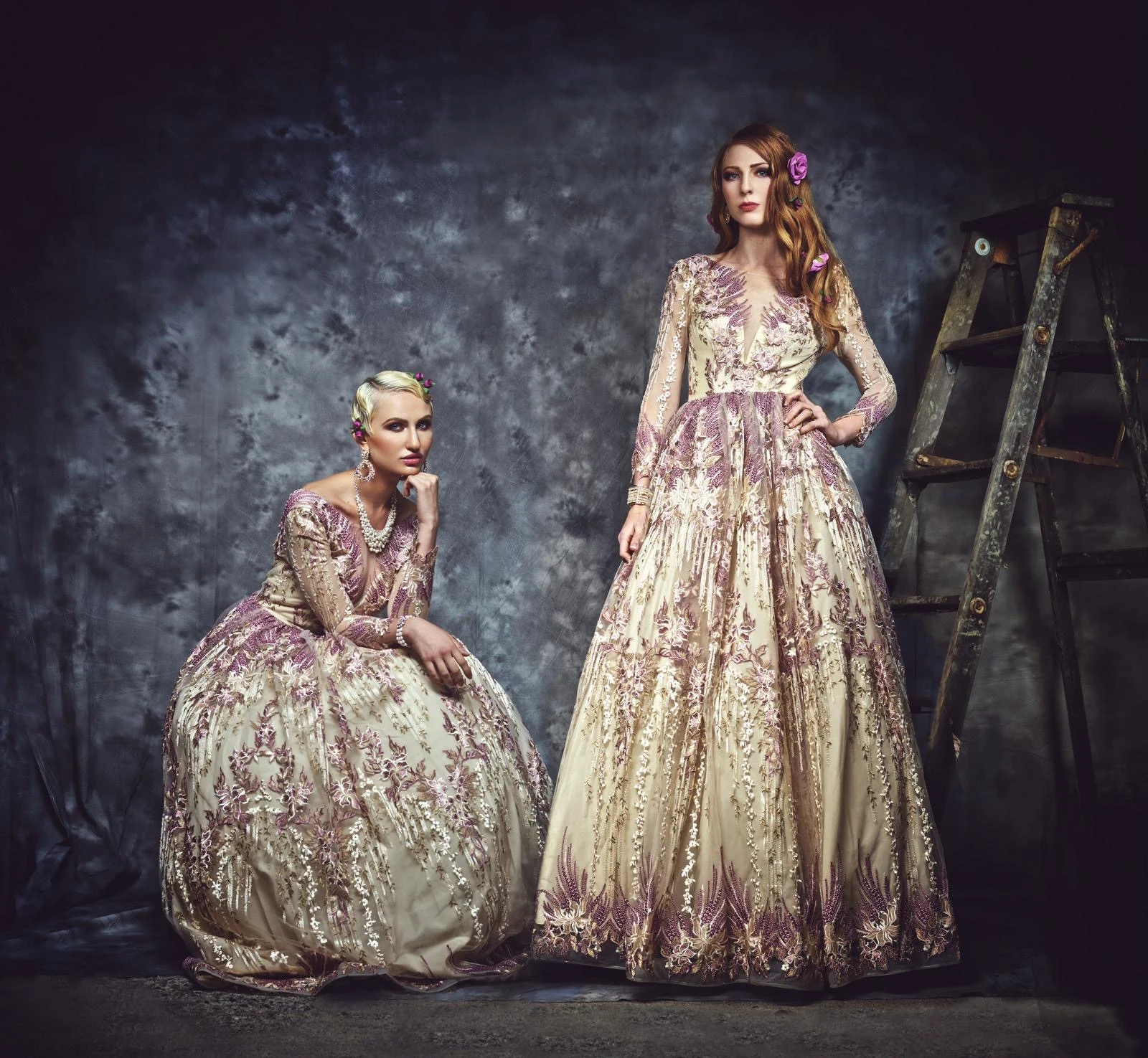 Two models wearing sculptural floral gowns against a textured backdrop