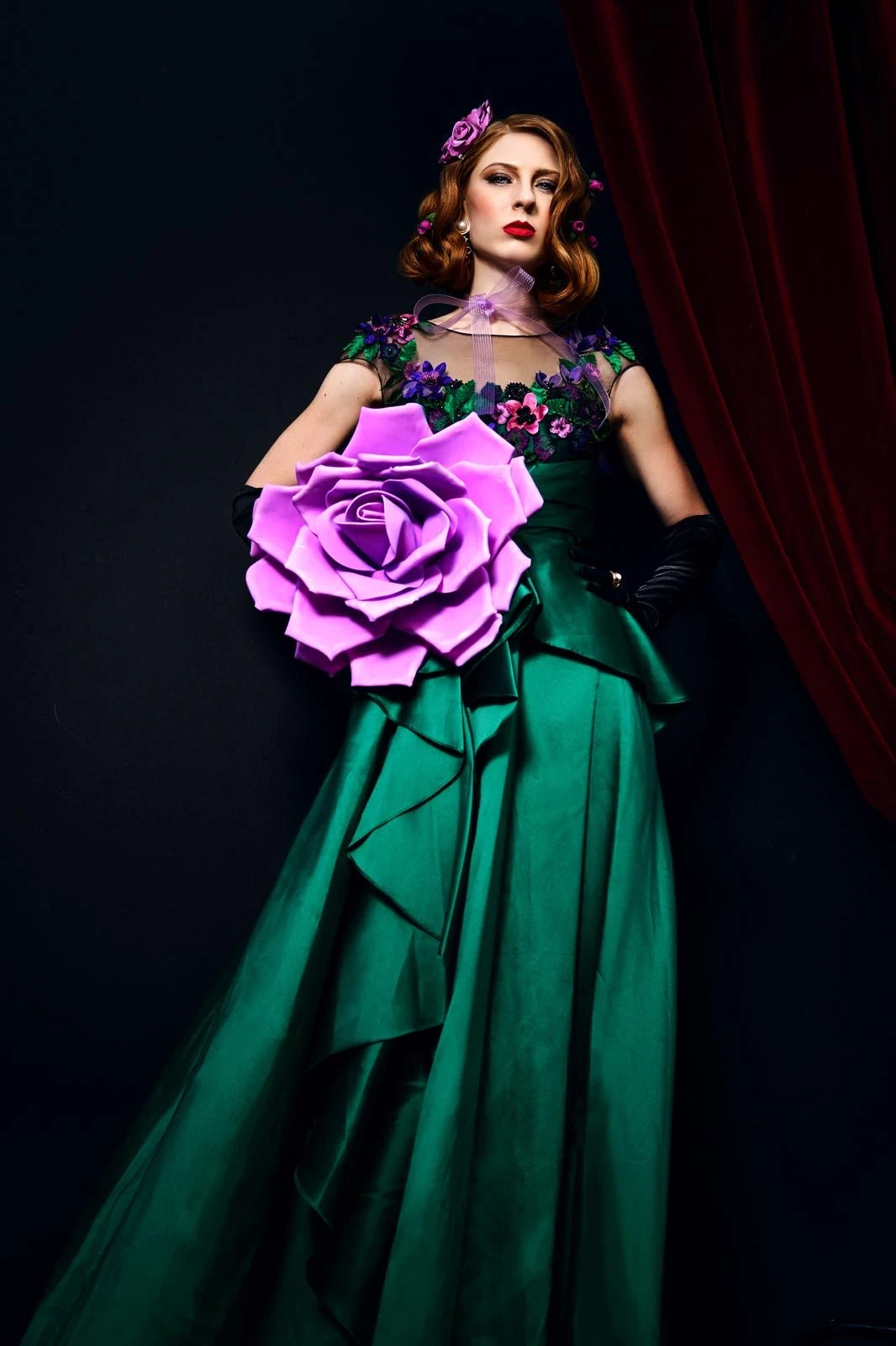 Green gown and an oversized purple flower in theatrical lighting