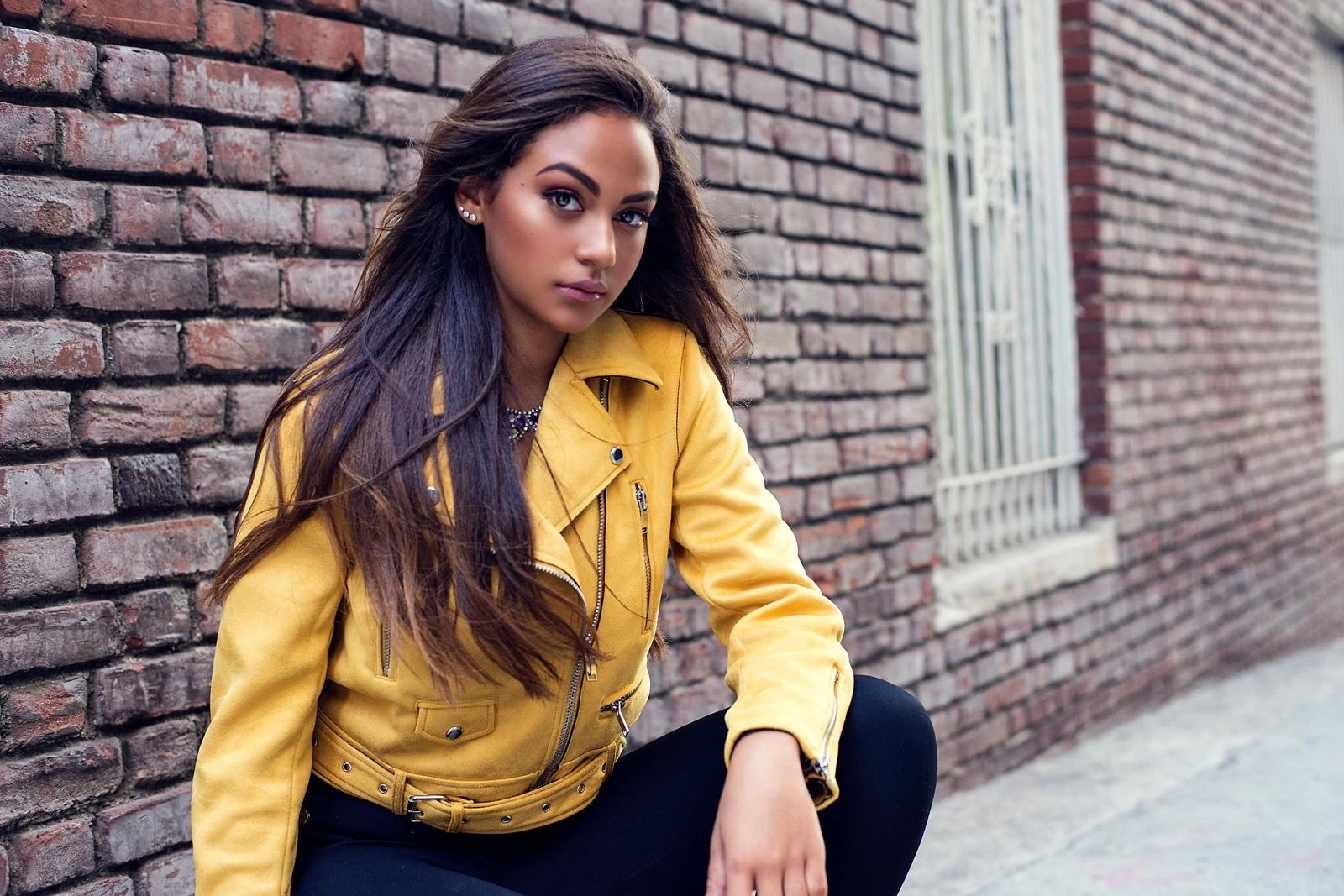 Yellow jacket fashion portrait beside a brick wall